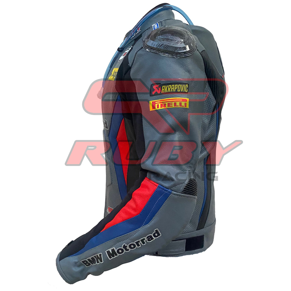 Left side view of the BMW Motorrad Racing Motorcycle Jacket. The gray leather jacket features sponsor logos including Akrapovic and Pirelli on the sleeve, with red and blue accents along the arm. The 'BMW Motorrad' branding is prominently displayed on the forearm, highlighting the jacket's racing-inspired design