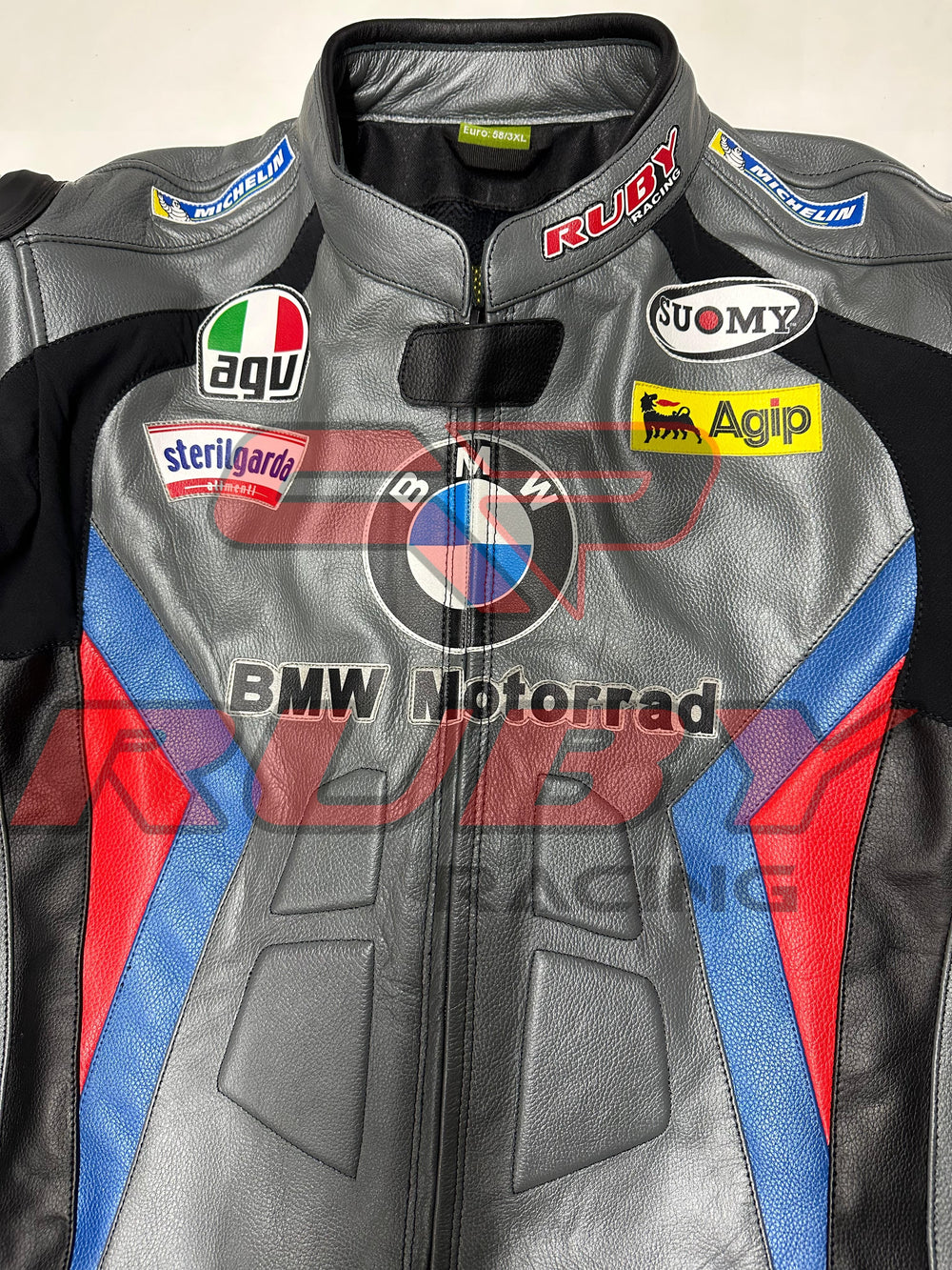 Front view of the BMW Motorrad Racing Motorcycle Jacket in gray with black, blue, and red detailing. The jacket displays prominent sponsor logos and is crafted from premium leather, ideal for motorbike riders seeking style and protection